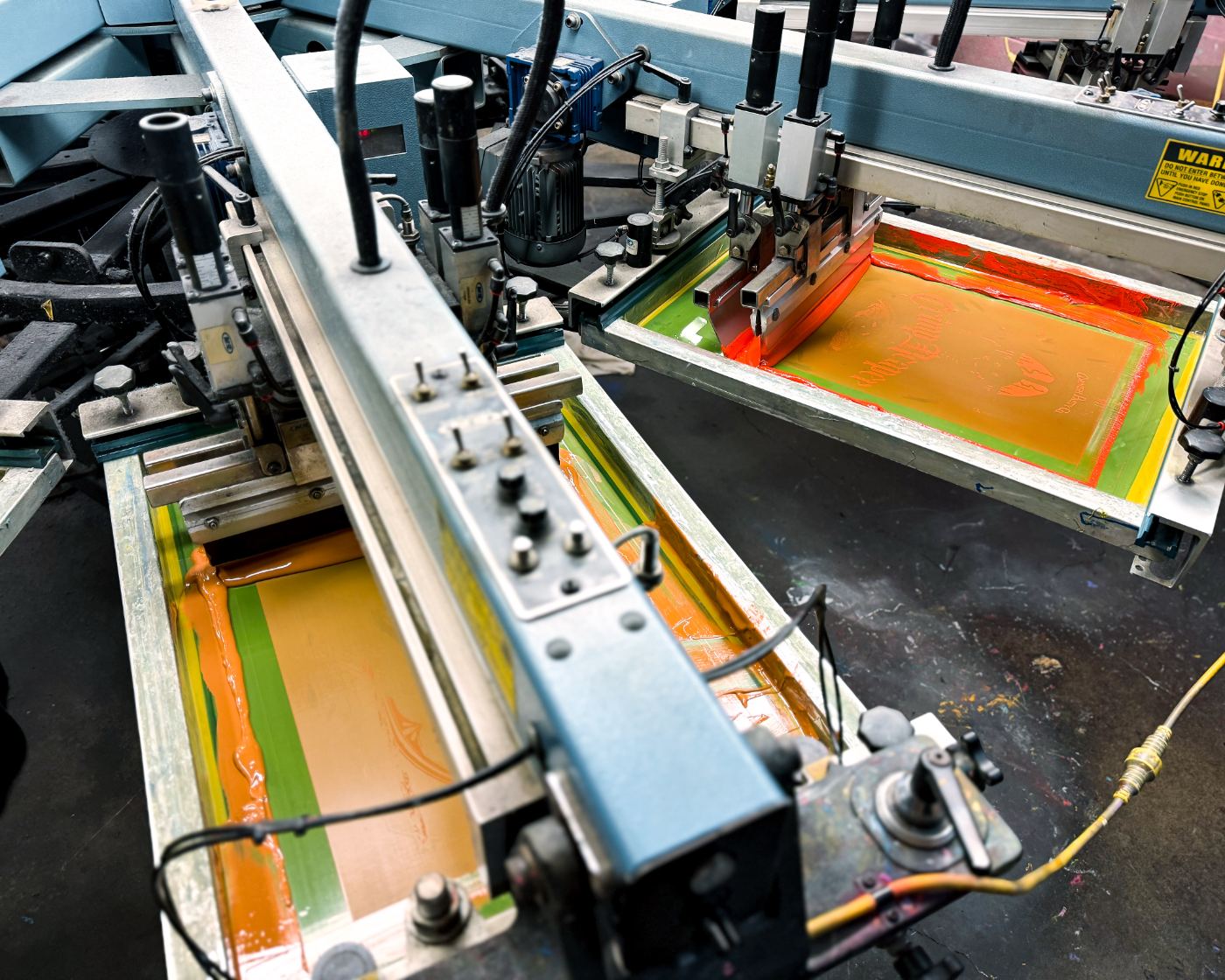 Screen printing frames loaded with orange ink ready for a production run